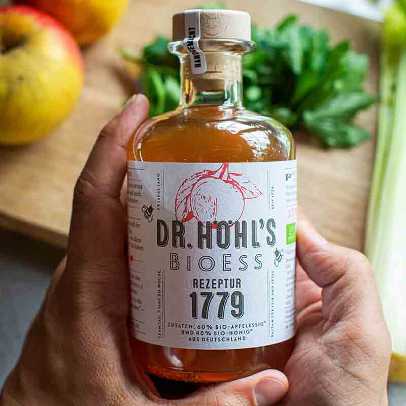 Dr. Höhl's Bioess Apfelessig Flasche in Händen gehalten.