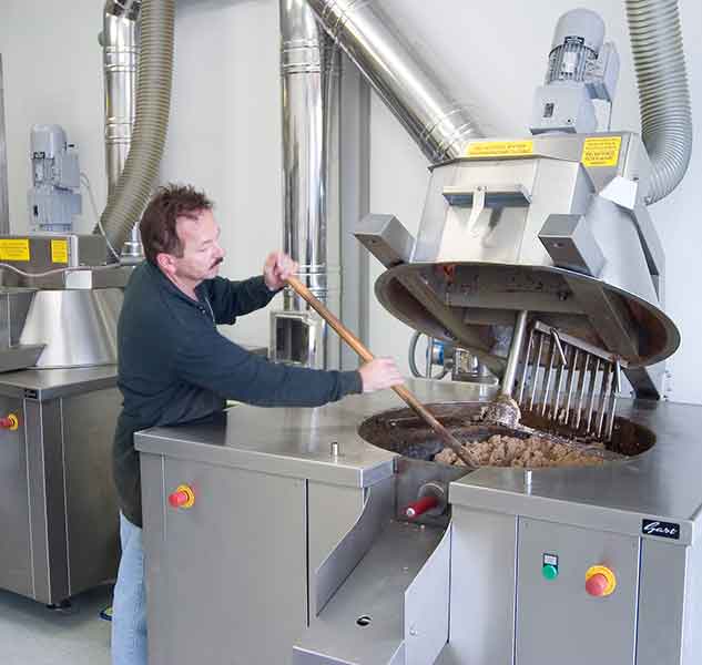 Mann rührt Olivenöl-Mischmaschine um.