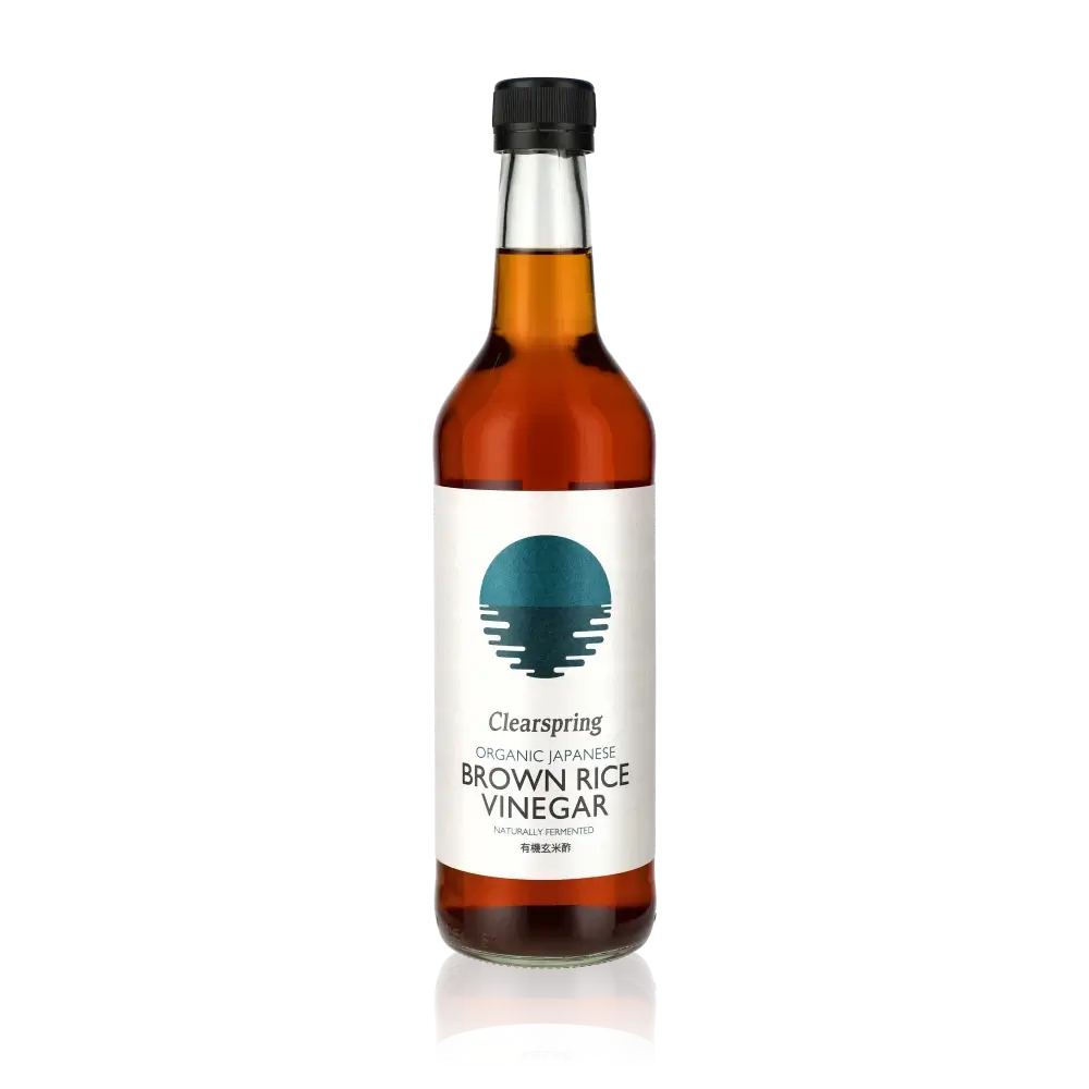 Clearspring brauner Reisessig Flasche vor schwarzem Hintergrund.