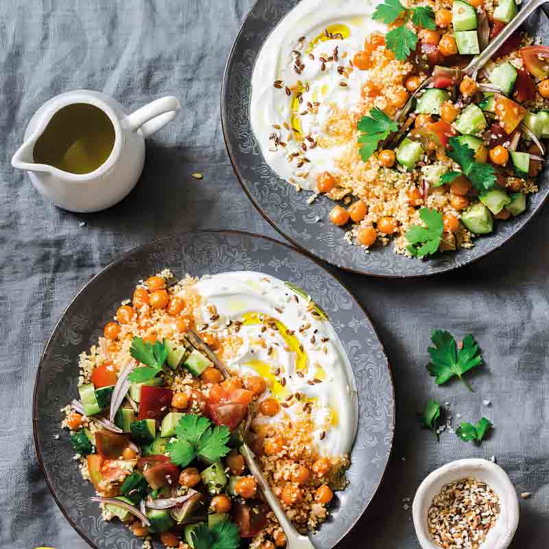 Zwei Teller Couscous-Salat mit Kichererbsen und Joghurt.