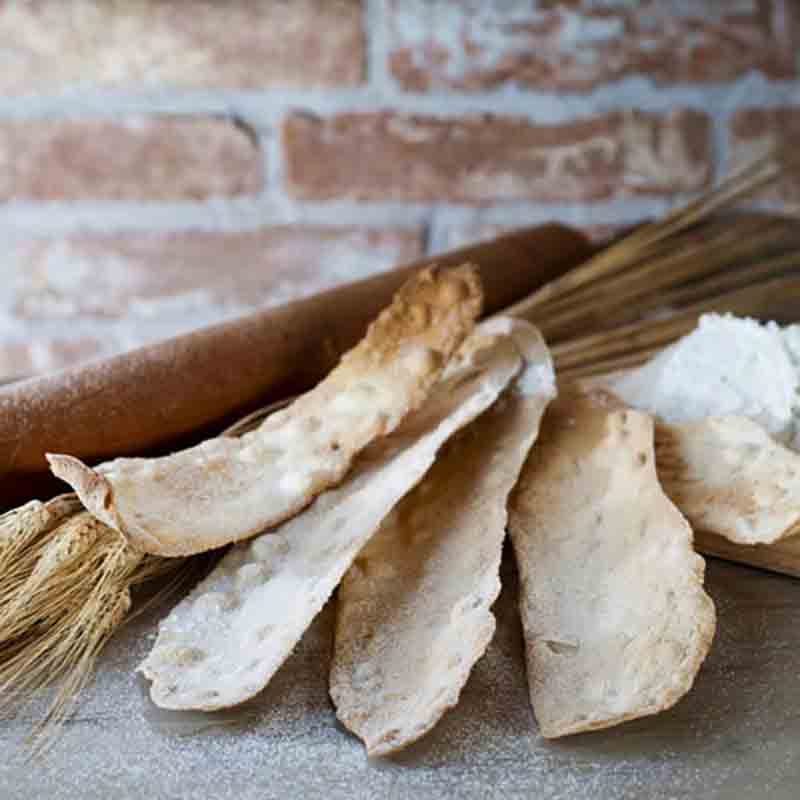 Feinkost: Brot, Mehl, Getreide vor Ziegelwand.