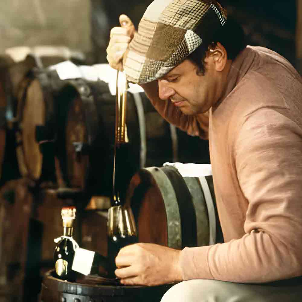 Mann füllt Balsamico-Essig aus Fass in Glas.