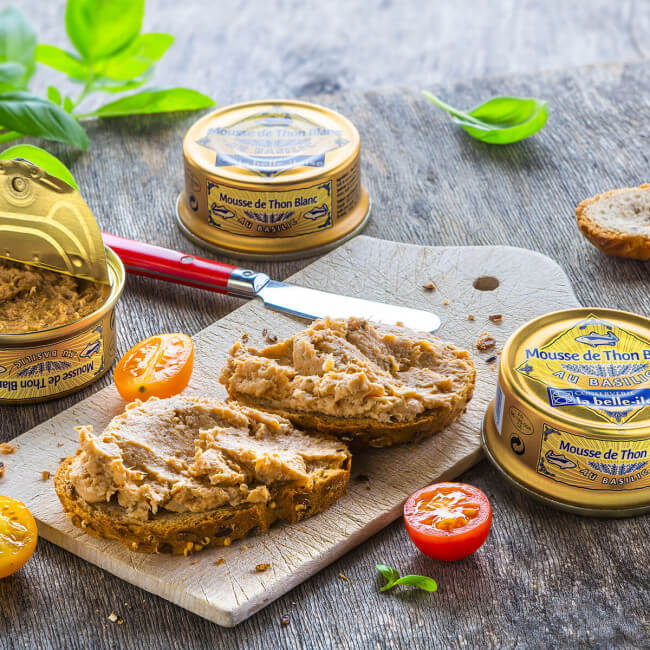 Thunfischmousse-Dosen, Brot, Tomaten, Basilikum auf Holzbrett.