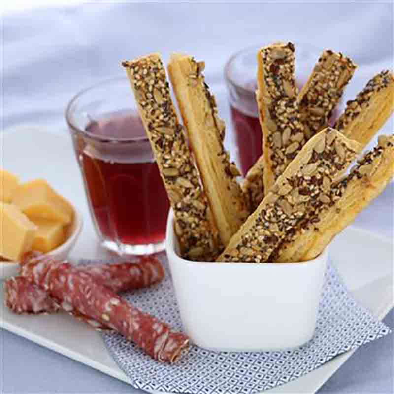 Blätterteiggebäck, Samen, Wurst, Käse, Rotwein auf Tisch.