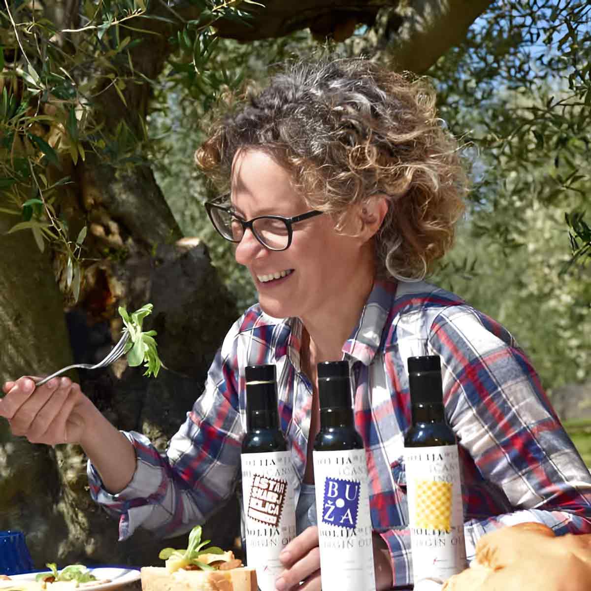 Person mit Olivenölflaschen draußen.