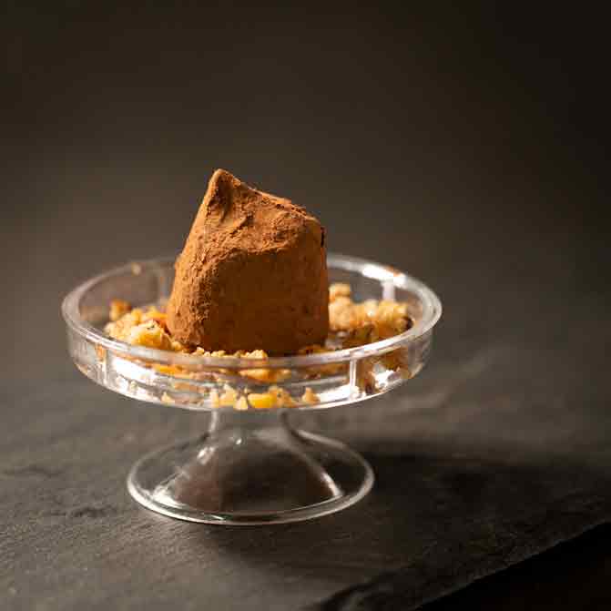 Praline auf Glasständer mit Nüssen dekoriert.