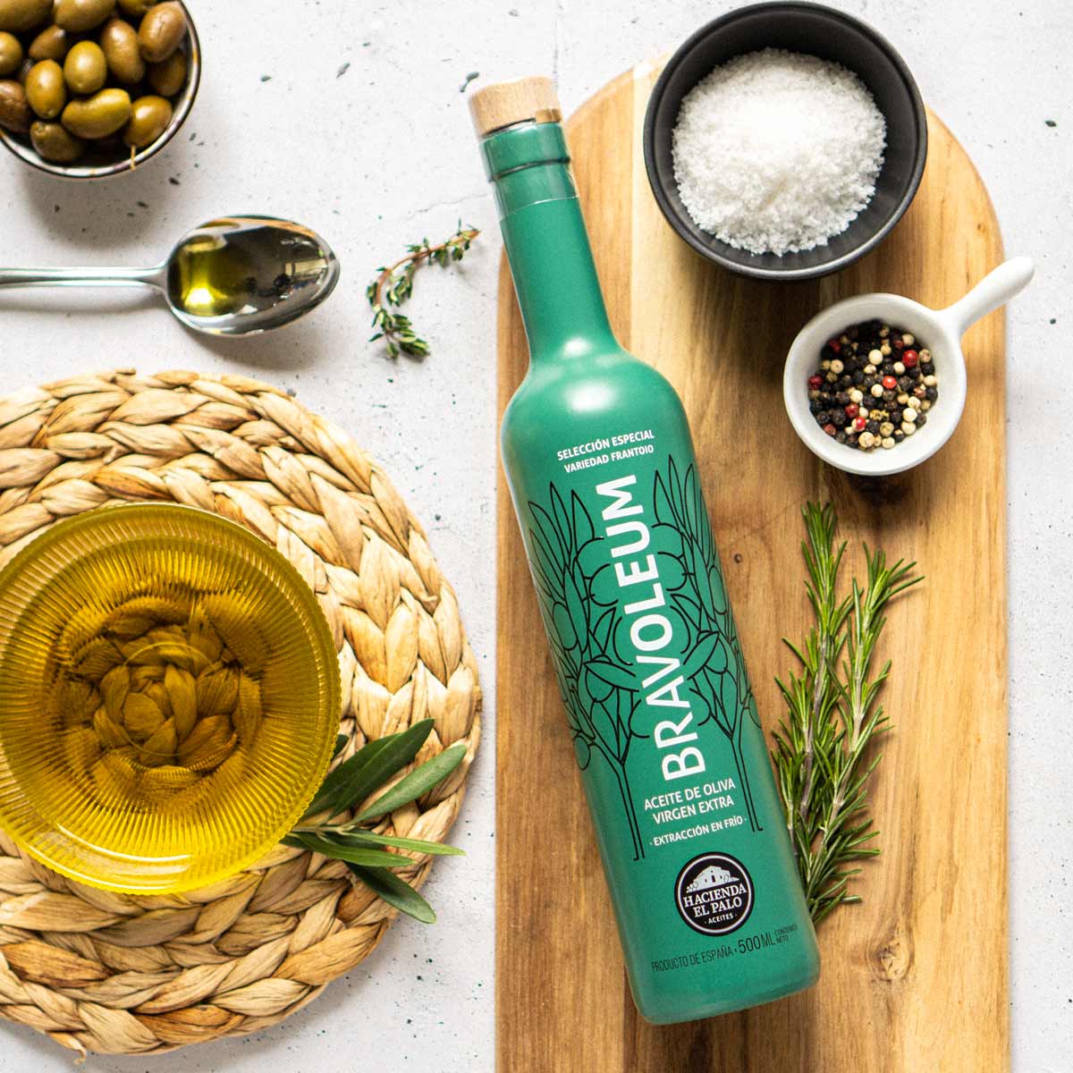 Bravoleum Olivenölflasche mit Gewürzen und Oliven auf Holzbrett.