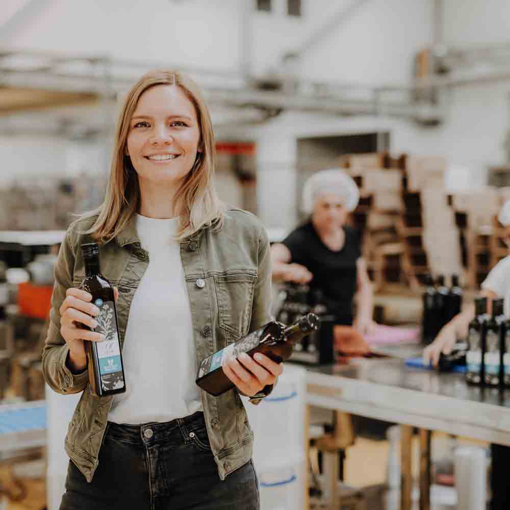 Person hält Flaschen mit Olivenöl in Produktionsumgebung.