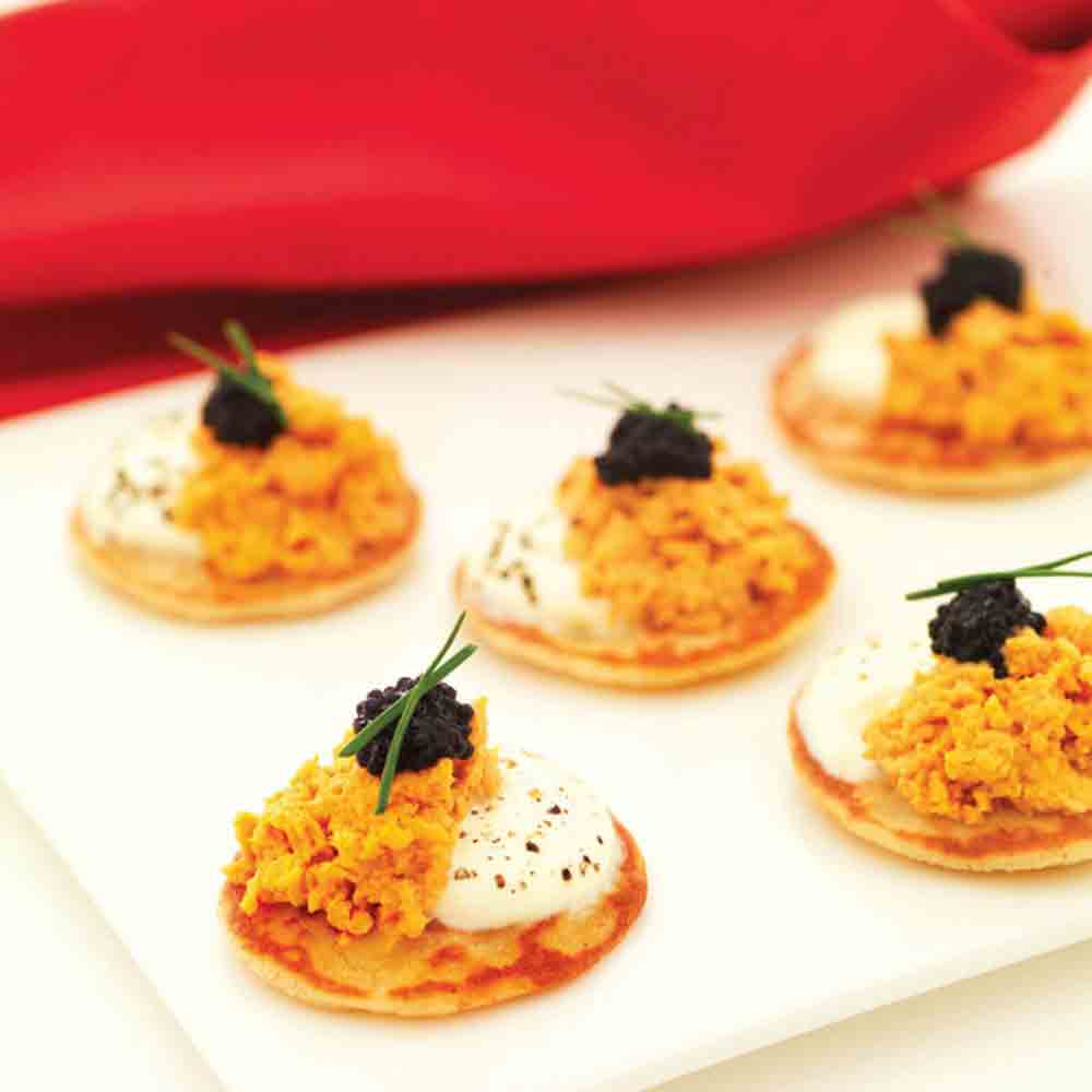 Kleine Häppchen mit Hummermousse und Kaviar auf Blinis.