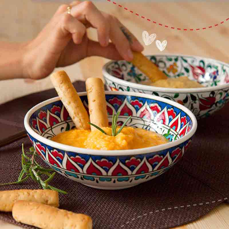 Zwei Schalen mit Grissini und Dip auf Tisch.