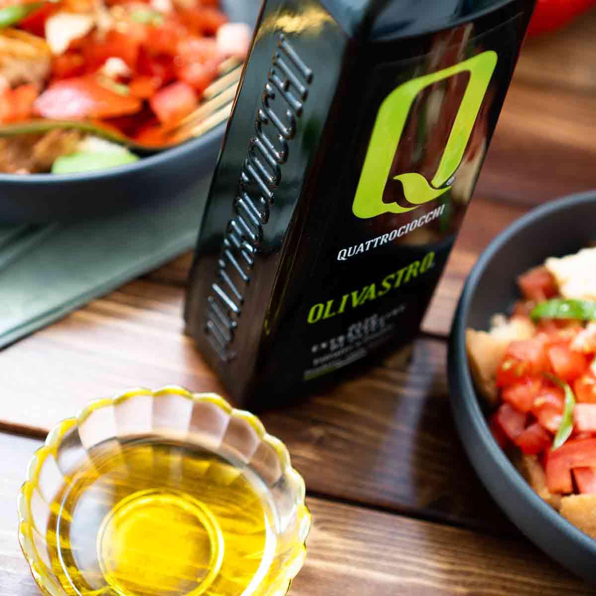 Quattrociocchi Olivastro Olivenöl neben Speisen und Schale.