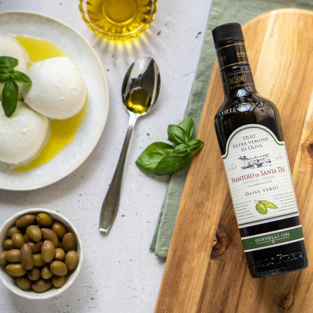 Olivenöl, Mozzarella, Oliven, Basilikum, Löffel, Holzbrett, Frantoio Santa Té.