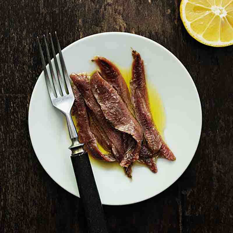 Sardellenfilets auf Teller mit Zitrone.