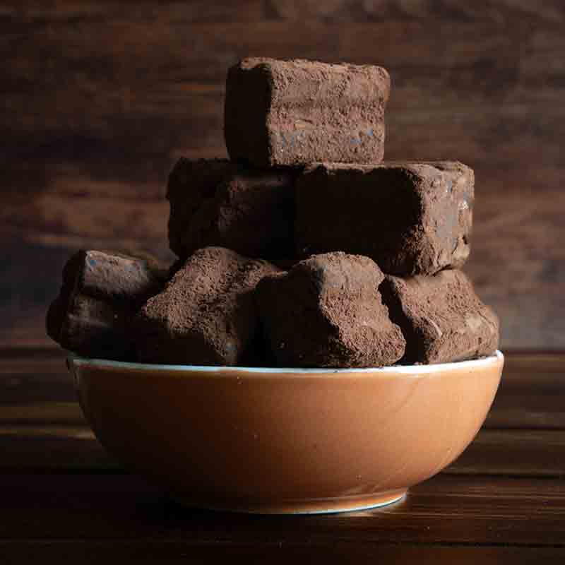 Feinkostschale mit Schokoladentrüffeln auf Holztisch.