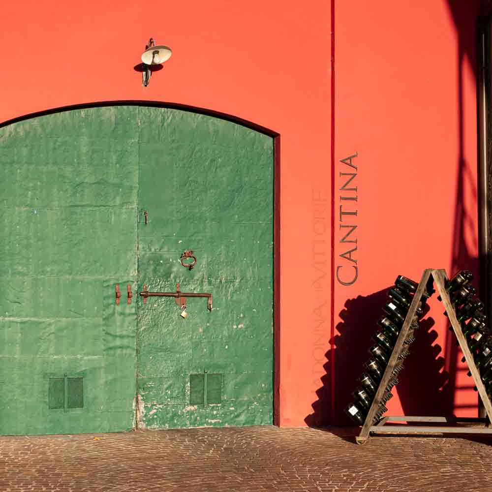 Grünes Tor, Cantina-Schriftzug, Weinflaschen auf Holzgestell.