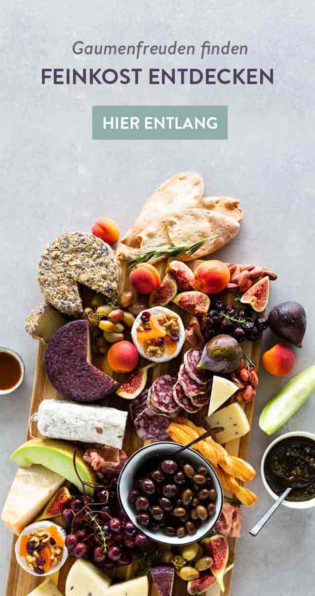Feinkostplatte mit Käse, Früchten, Oliven, Brot und Aufschnitt.