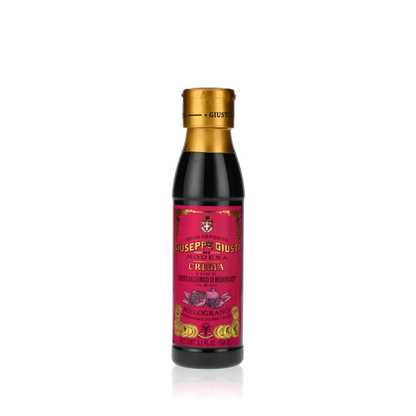 Giuseppe Giusti Crema Granatapfel Balsamicocreme Flasche auf schwarzem Hintergrund.