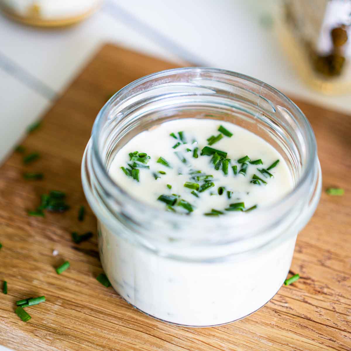 Blick von oben in das Joghurt-Dressing. Frisch geschnittener Schnittlauch ist im Dressing zu sehen.