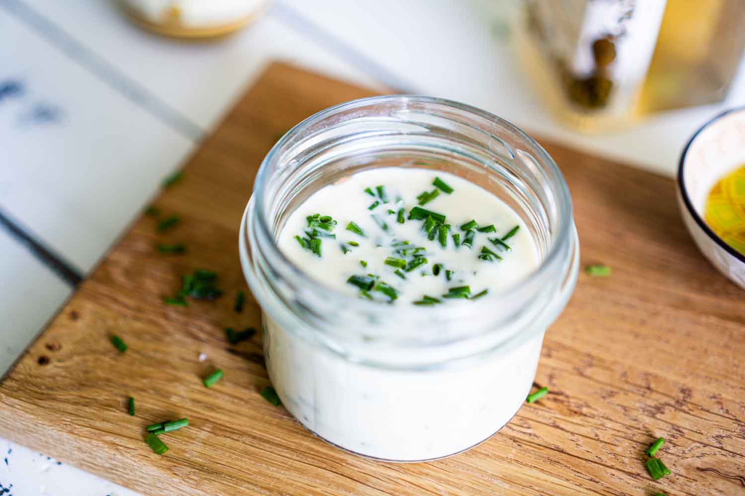 Blick von oben in das Joghurt-Dressing. Frisch geschnittener Schnittlauch ist im Dressing zu sehen.