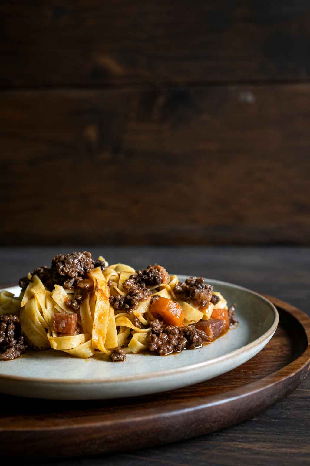 Tagliatelle mit Ragù alla Bolognese auf einem Teller auf einem Holztisch